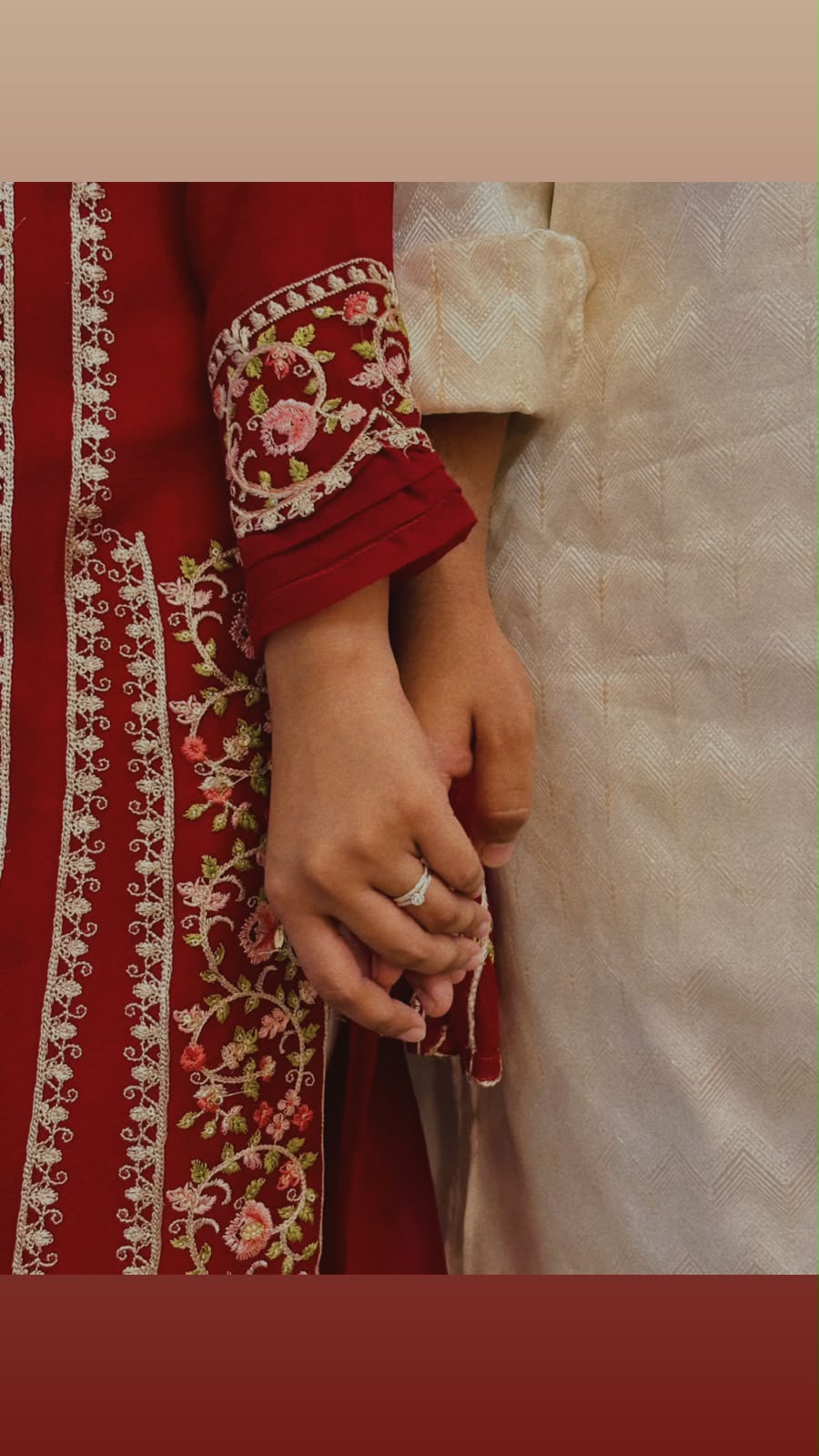Couple holding hands in red and ivory wedding attire