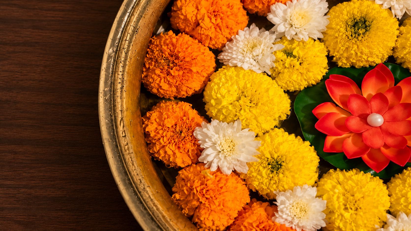 Marigold flowers and a red lotus in a brass bowl